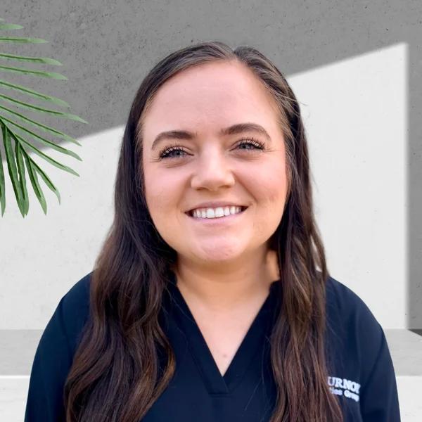 A smiling professional portrait with a plant in the background.