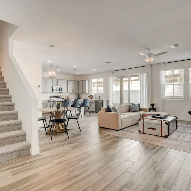 Stylish Open-Concept Living Room Spacious modern living room with an open layout, featuring a staircase, a dining area, and large windows.