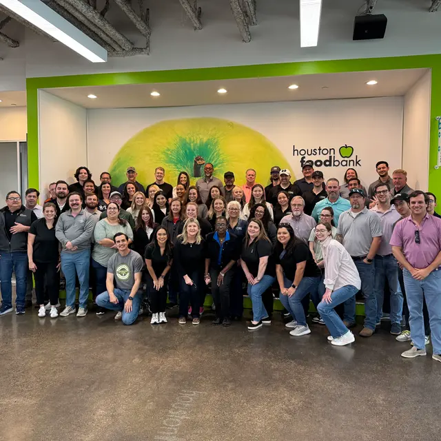Group Photo at Houston Food Bank Large group photo of people in a gathering at the Houston Food Bank, standing in front of a colorful mural.