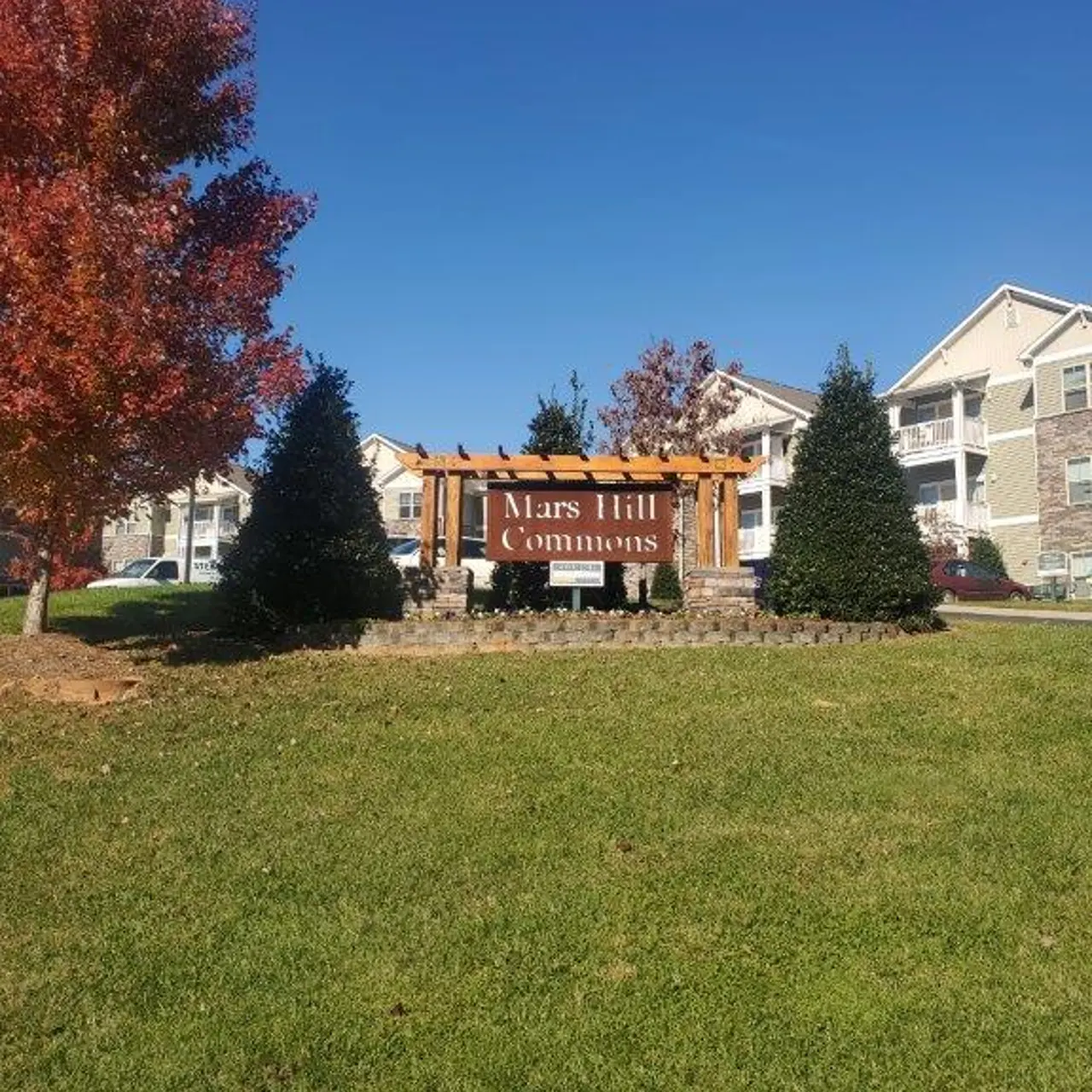 Sign for Mars Hill Commons surrounded by trees and grass on a sunny day.