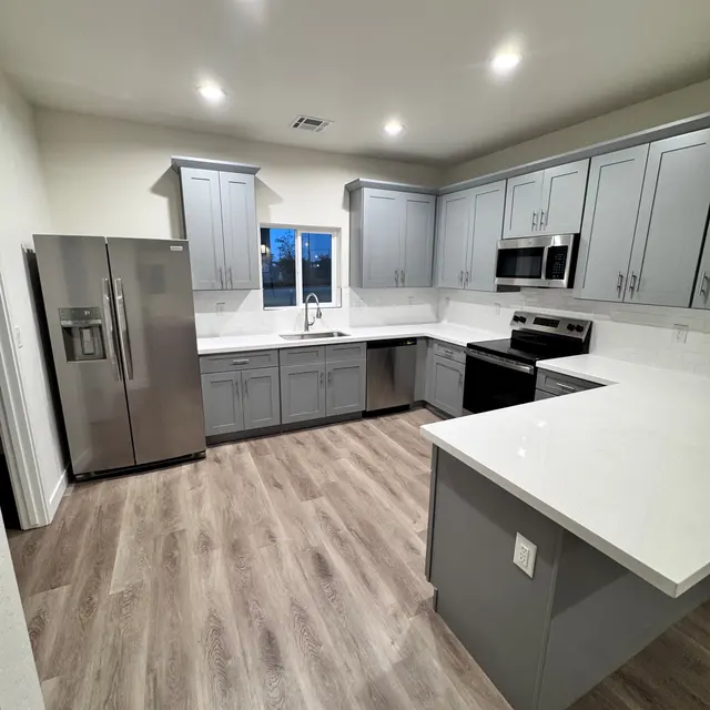 Modern Kitchen Design A modern kitchen featuring light gray cabinets, white countertops, stainless steel appliances, and wooden flooring.