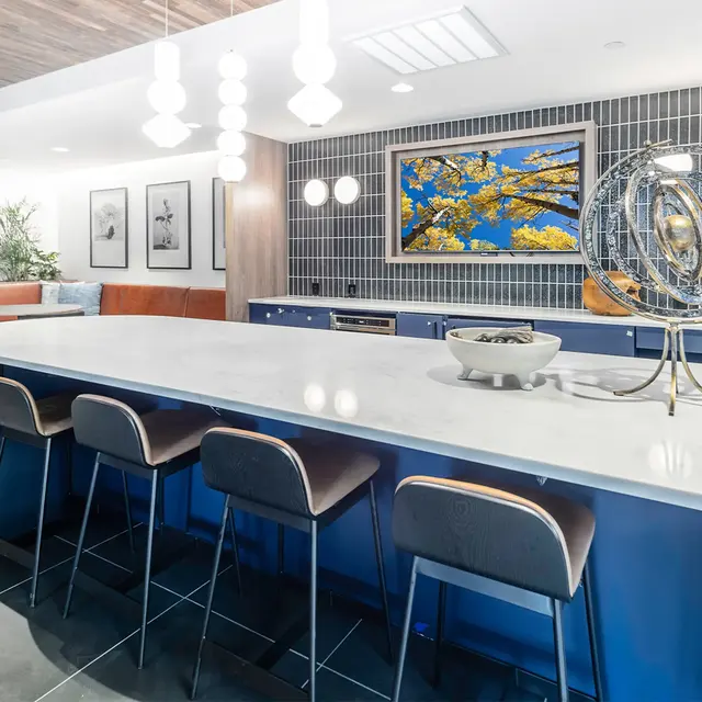 A modern kitchen space featuring an island with bar stools, decorative art on the wall, and a stylish interior design.