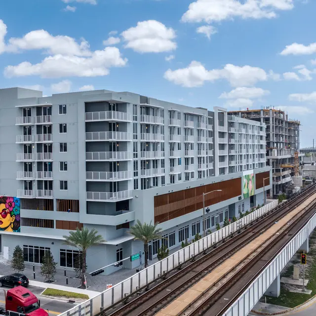 Modern apartment building with colorful mural and train tracks nearby