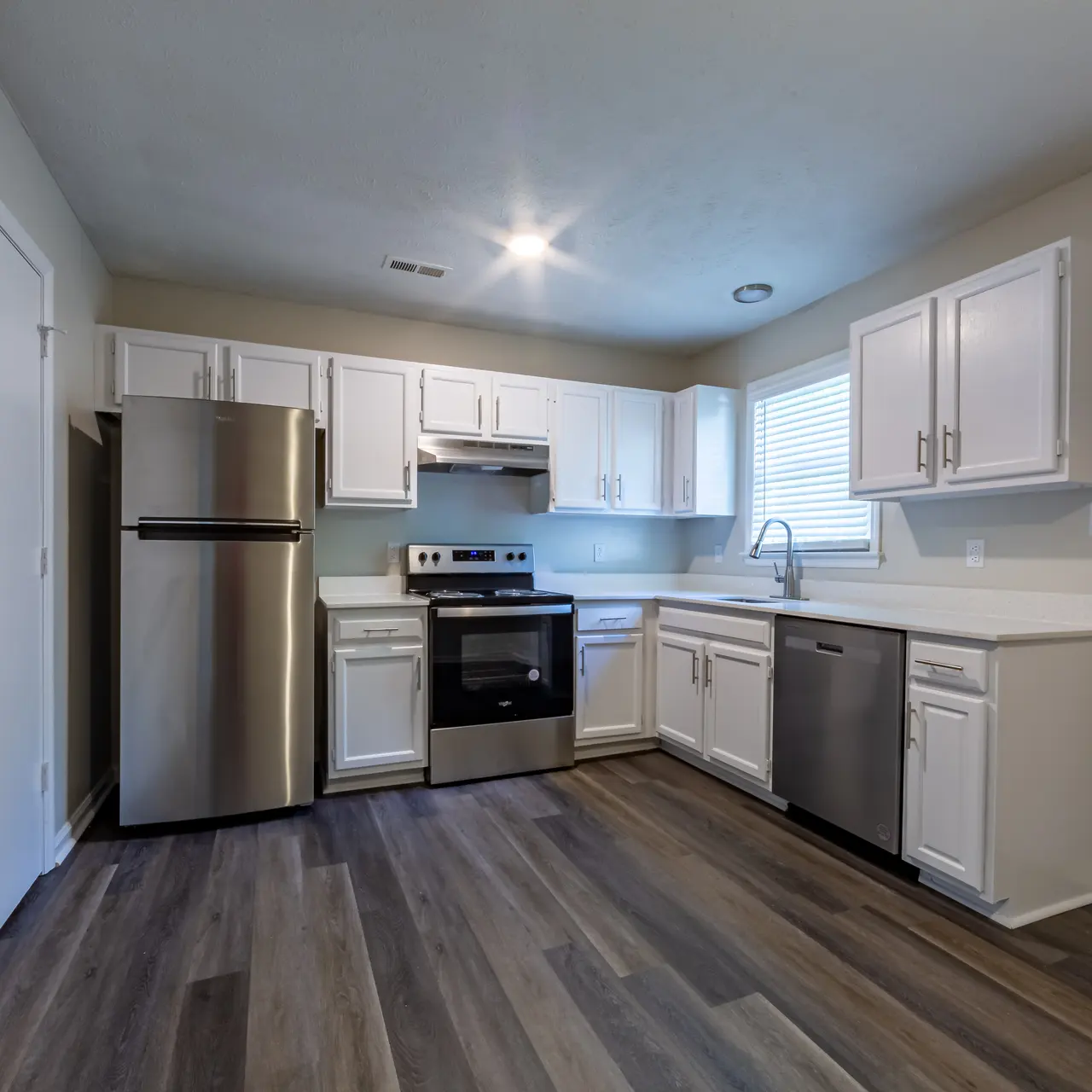 A modern kitchen featuring white cabinets, stainless steel appliances, and a combination of countertop and floor space.
