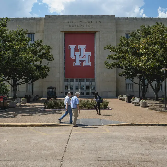 University of Houston Exterior view of the Cullen Building at the University of Houston, featuring the UH logo on a large banner and trees in front.