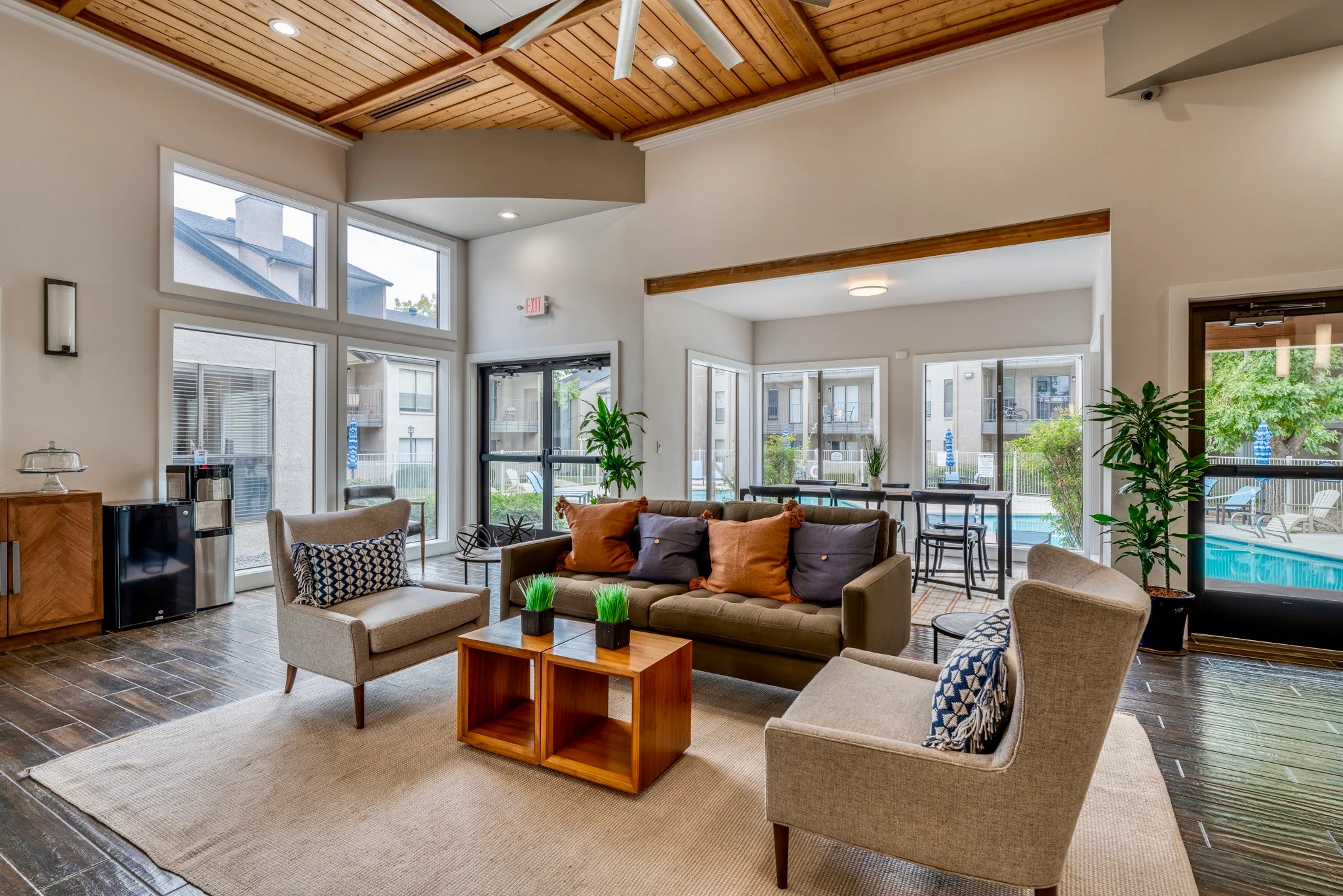 Community Lounge Space A modern community lounge space with a cozy seating arrangement, featuring a sofa and armchairs around a coffee table. Large windows let in natural light, and plants add greenery to the space.