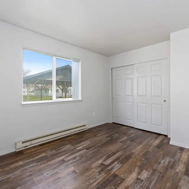 Bright Empty Room A bright, empty room with white walls and wooden flooring. A large window allows natural light to fill the space.