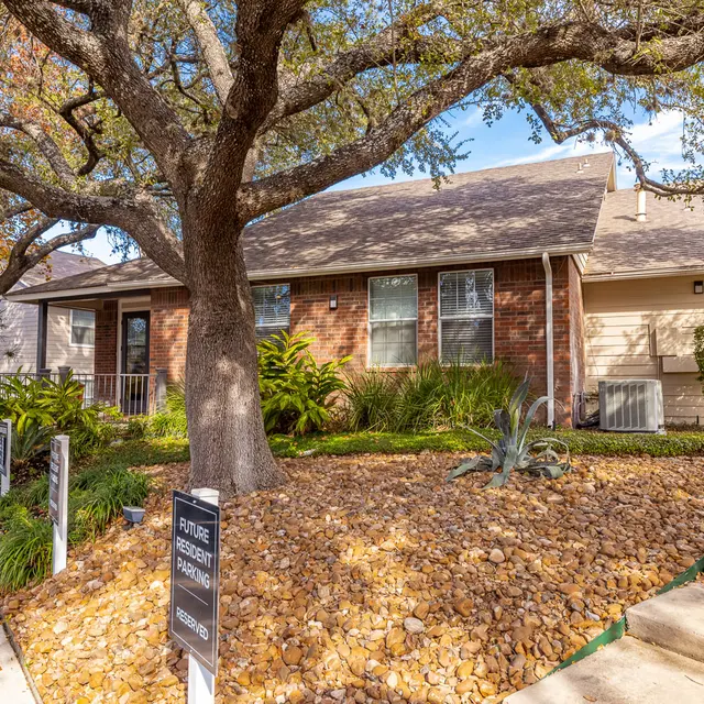 Charming Brick House Exterior A view of a brick house surrounded by greenery and landscaped stone pathways.