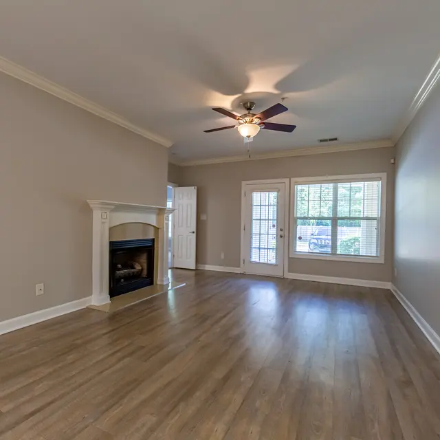 Spacious living room featuring natural light from large windows, a ceiling fan, and a fireplace.