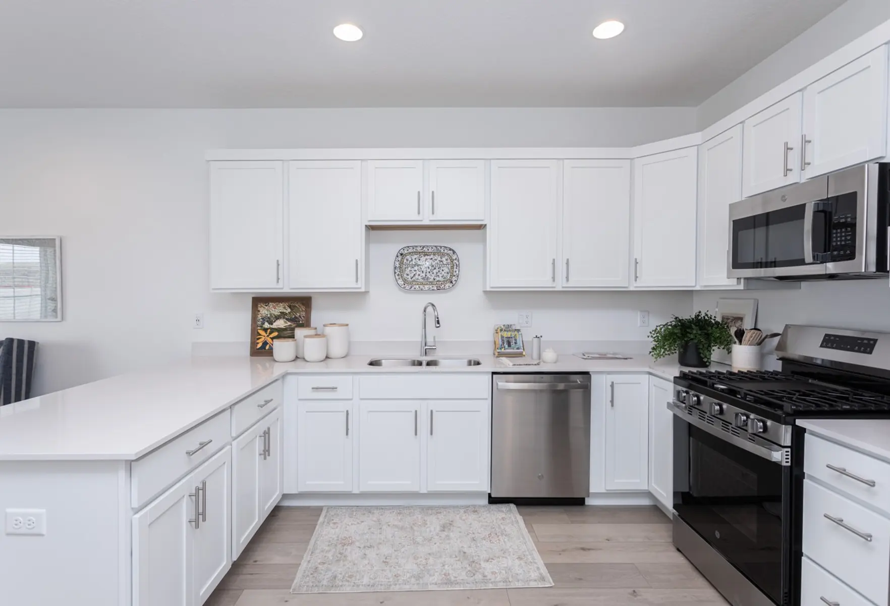 Modern Kitchen Design A modern kitchen with white cabinetry and stainless steel appliances, featuring a spacious countertop and a decorative rug.