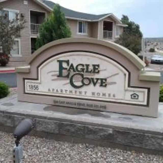 Eagle Cove Apartment Homes Sign Sign for Eagle Cove Apartment Homes with a stone base, surrounded by shrubs and a parking area in the background.