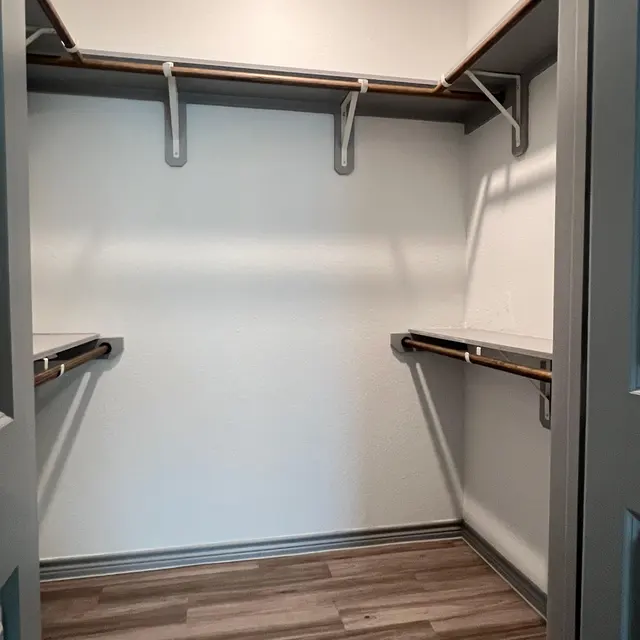 An empty closet with wooden shelves and laminate flooring.