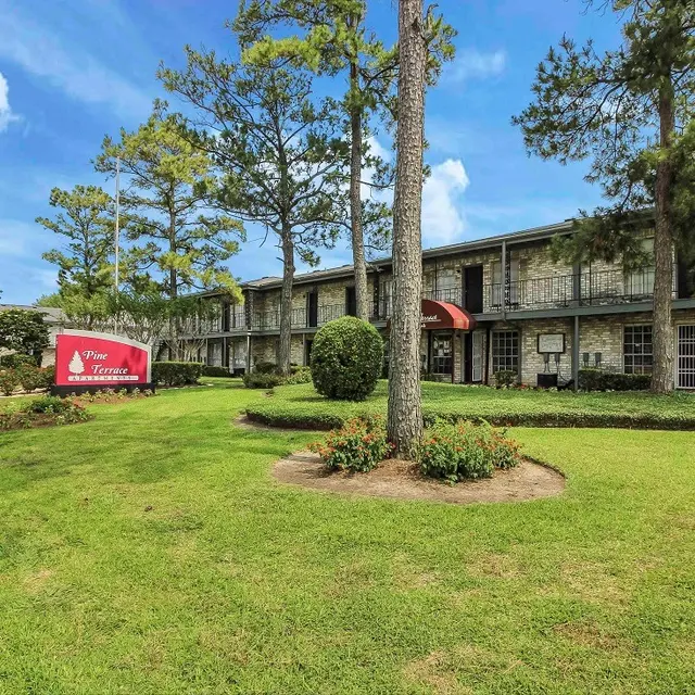 Exterior view of an apartment complex with well-maintained landscaping and signage.