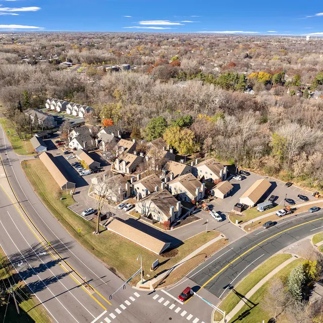 Aerial view of a residential area featuring various houses and roads surrounded by trees in autumn colors.
