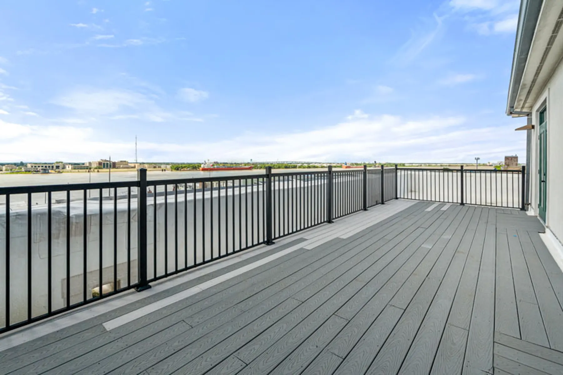 Wide balcony with gray flooring and black railing overlooking a landscape