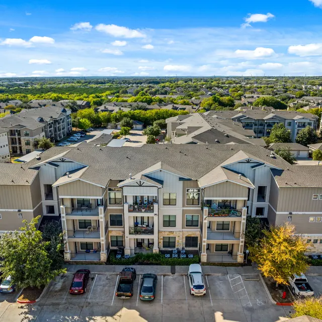 Aerial view of an apartment complex surrounded by greenery and parking lots.