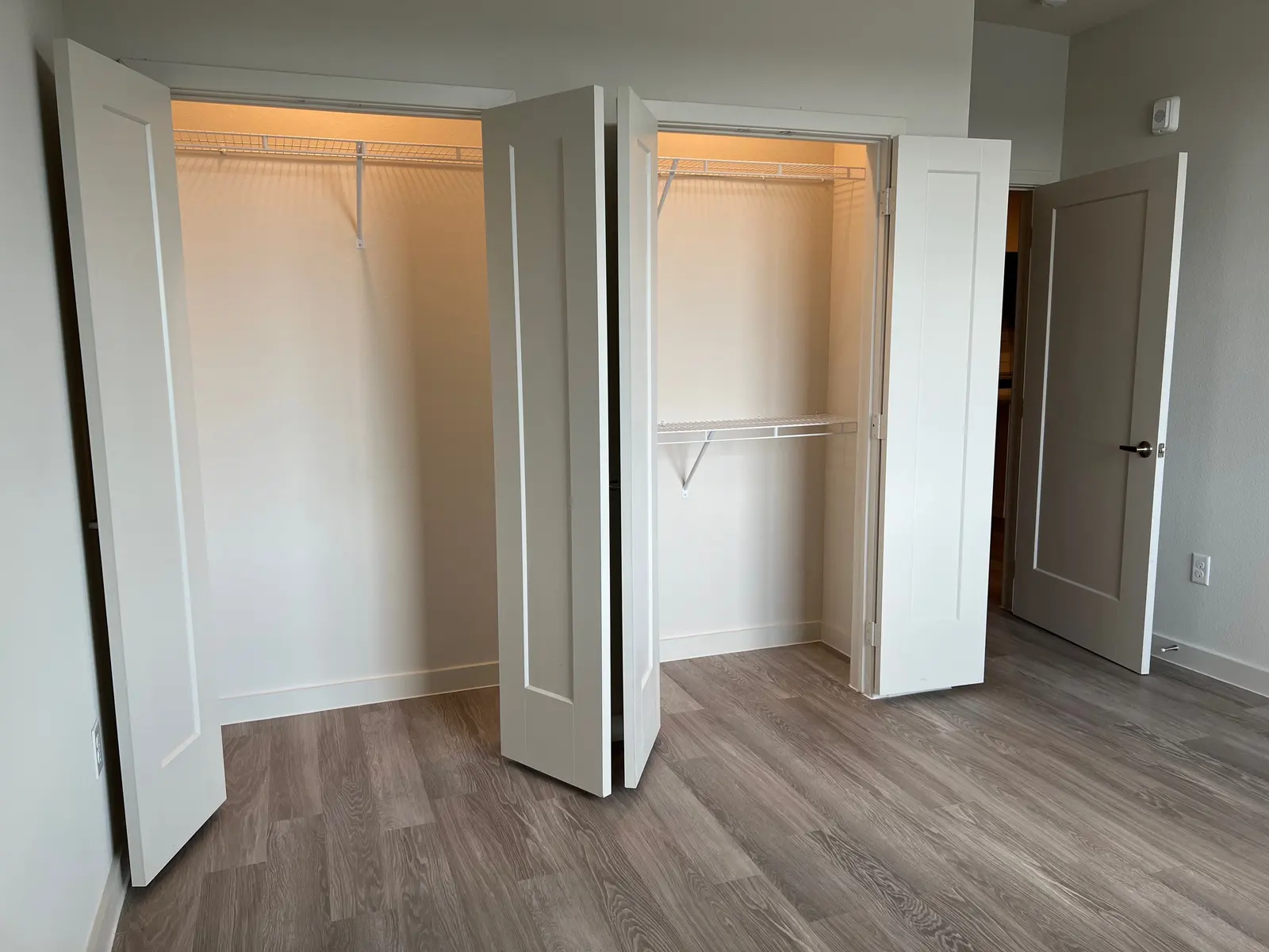 Interior view of two open closet doors revealing empty wire shelving and lighted interiors.
