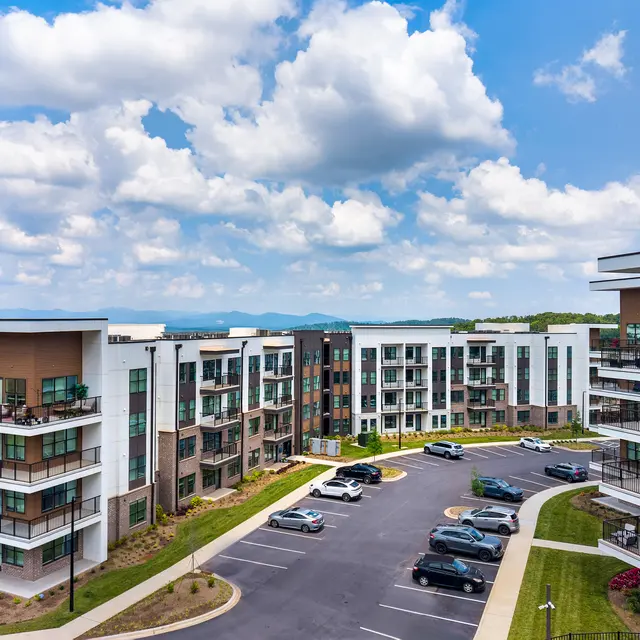 Aerial view of a modern apartment complex with multiple buildings and green landscaping.