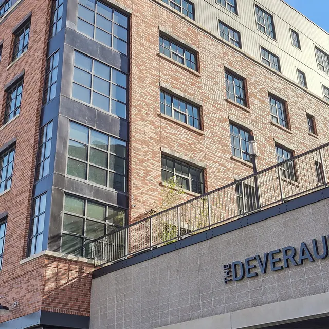 The Deveraux Building A modern building with a mix of brick and glass architecture, featuring multiple windows and balconies, with an entrance sign that reads 'THE DEVERAUX.'