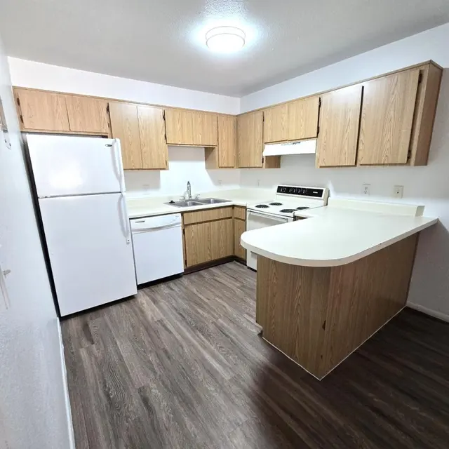 Spacious Modern Kitchen A modern kitchen featuring light wood cabinetry, white appliances, and a spacious layout with a wooden floor.