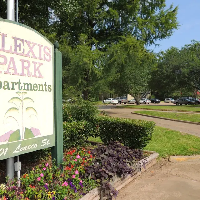 Alexis Park Apartments Entrance Sign for Alexis Park Apartments, featuring greenery and a flower bed in front of the entrance.