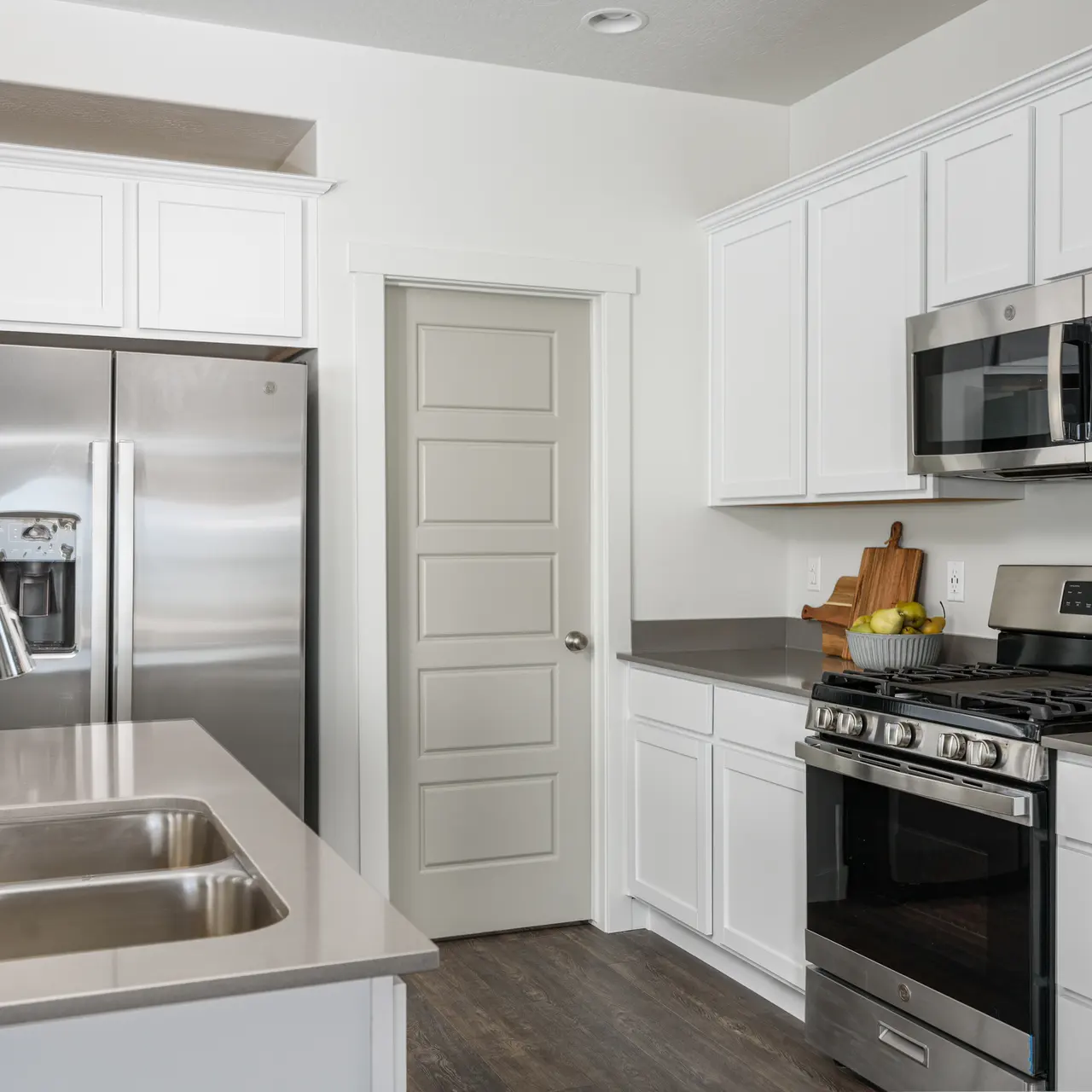 A modern kitchen featuring white cabinets, stainless steel appliances, and a spacious island with a sink.