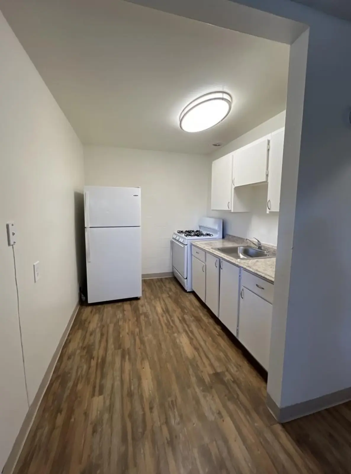 Kitchen with white cabinets, refrigerator, stove and sink.