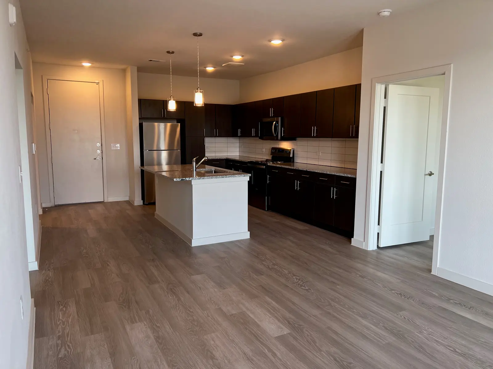 A modern kitchen in an apartment with dark cabinets, stainless steel appliances, and a central island.