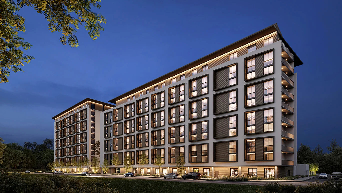 A modern apartment building illuminated at night, showcasing multiple stories and large windows.
