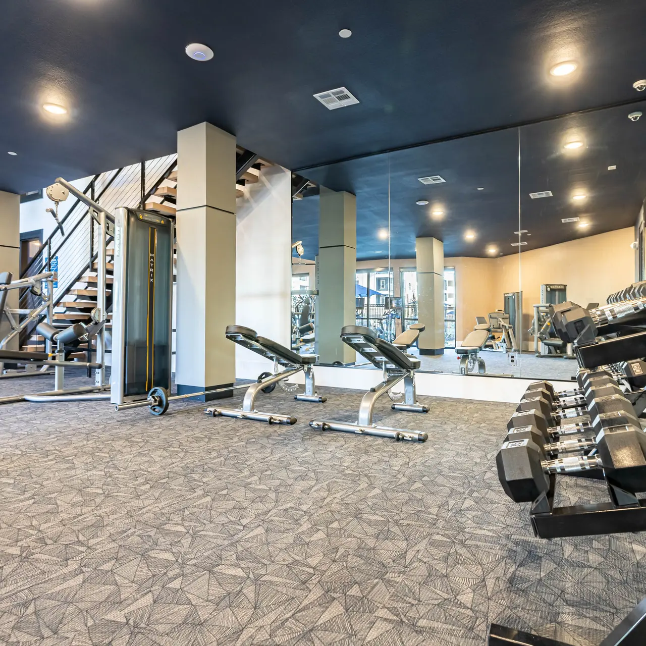 Interior view of a modern gym with workout equipment and mirrors.