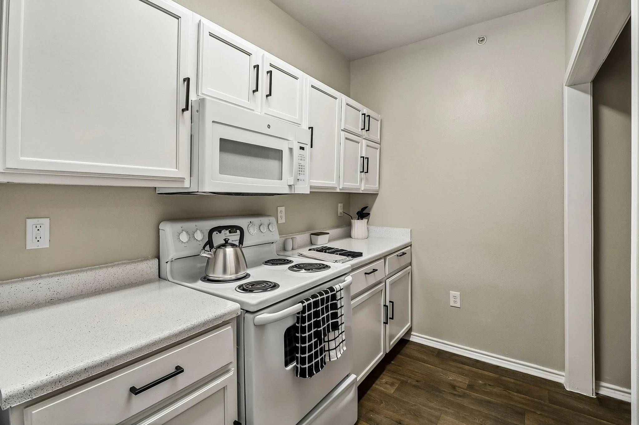 Interior view of a modern kitchen featuring white cabinetry, a stove, and a microwave.