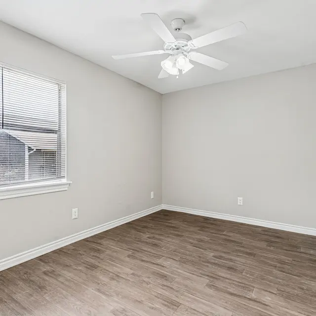 An empty room featuring a ceiling fan and a window with blinds.