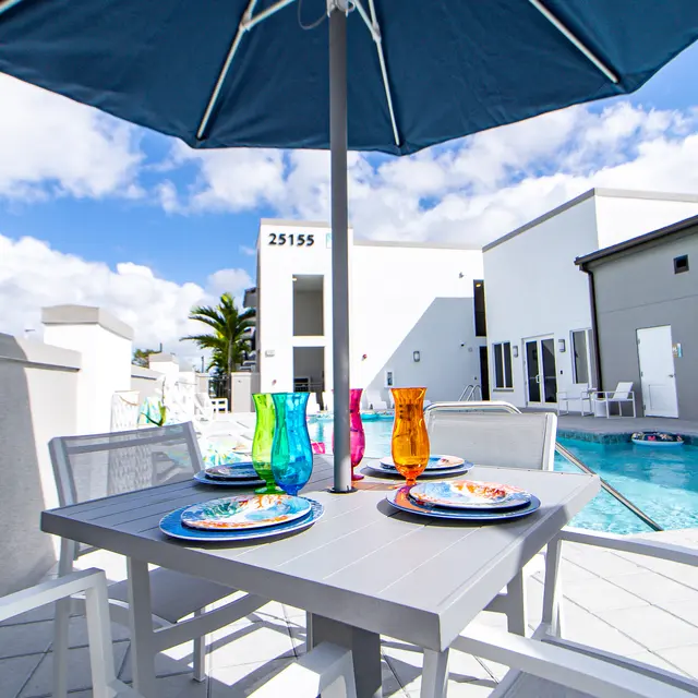 Colorful Outdoor Dining by the Pool An outdoor dining setup with colorful glasses and plates next to a swimming pool.