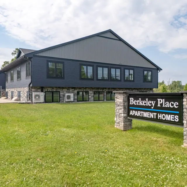 Exterior view of the Berkeley Place Apartment Homes building, featuring a modern design and a grassy area in the foreground.