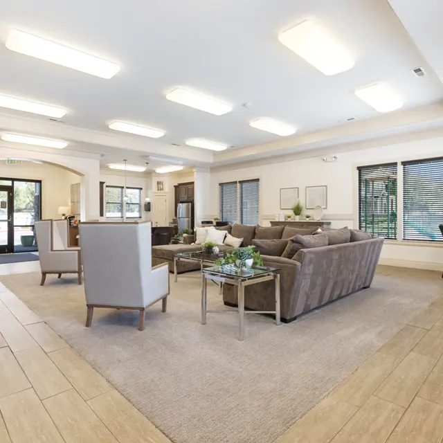 A spacious lobby area featuring comfortable seating and a large rug, with natural light coming from large windows.