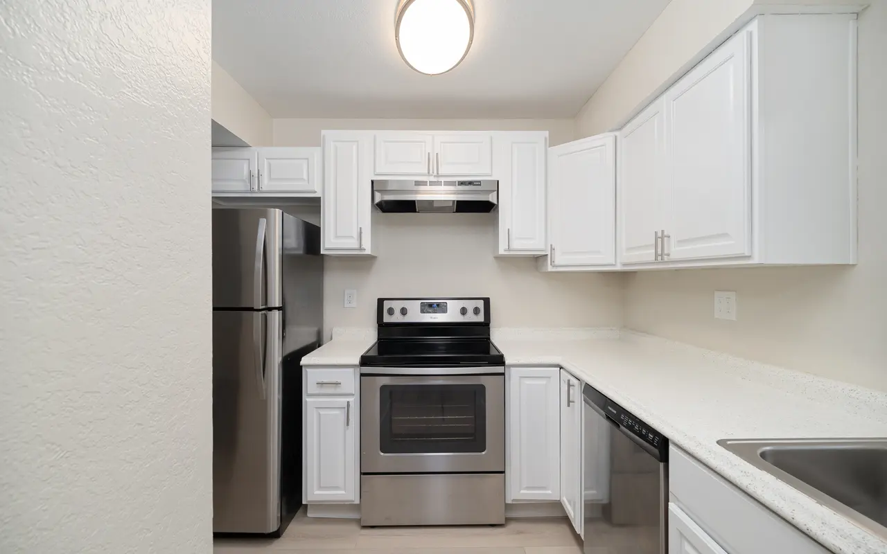 A modern kitchen with white cabinets, stainless steel appliances, and a light-colored countertop.