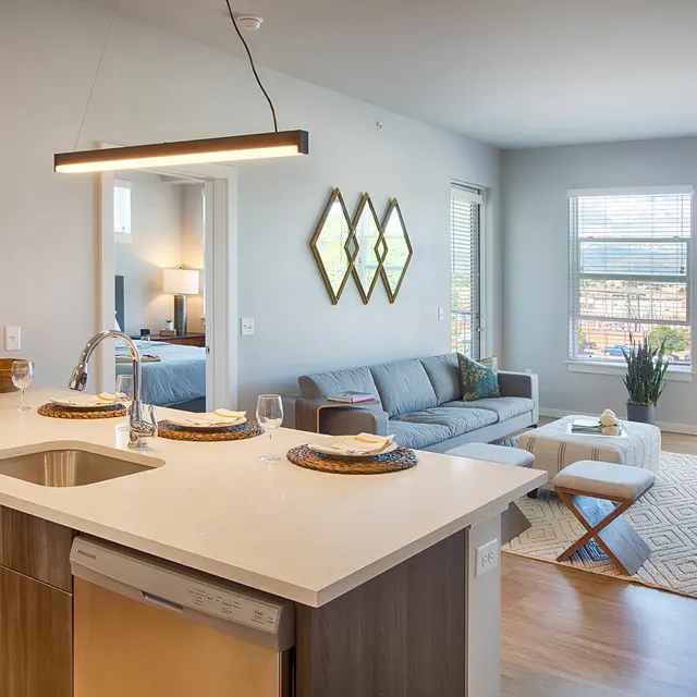 Modern apartment interior featuring a kitchen with island, living area, and large windows with natural light. Stylish decor throughout.