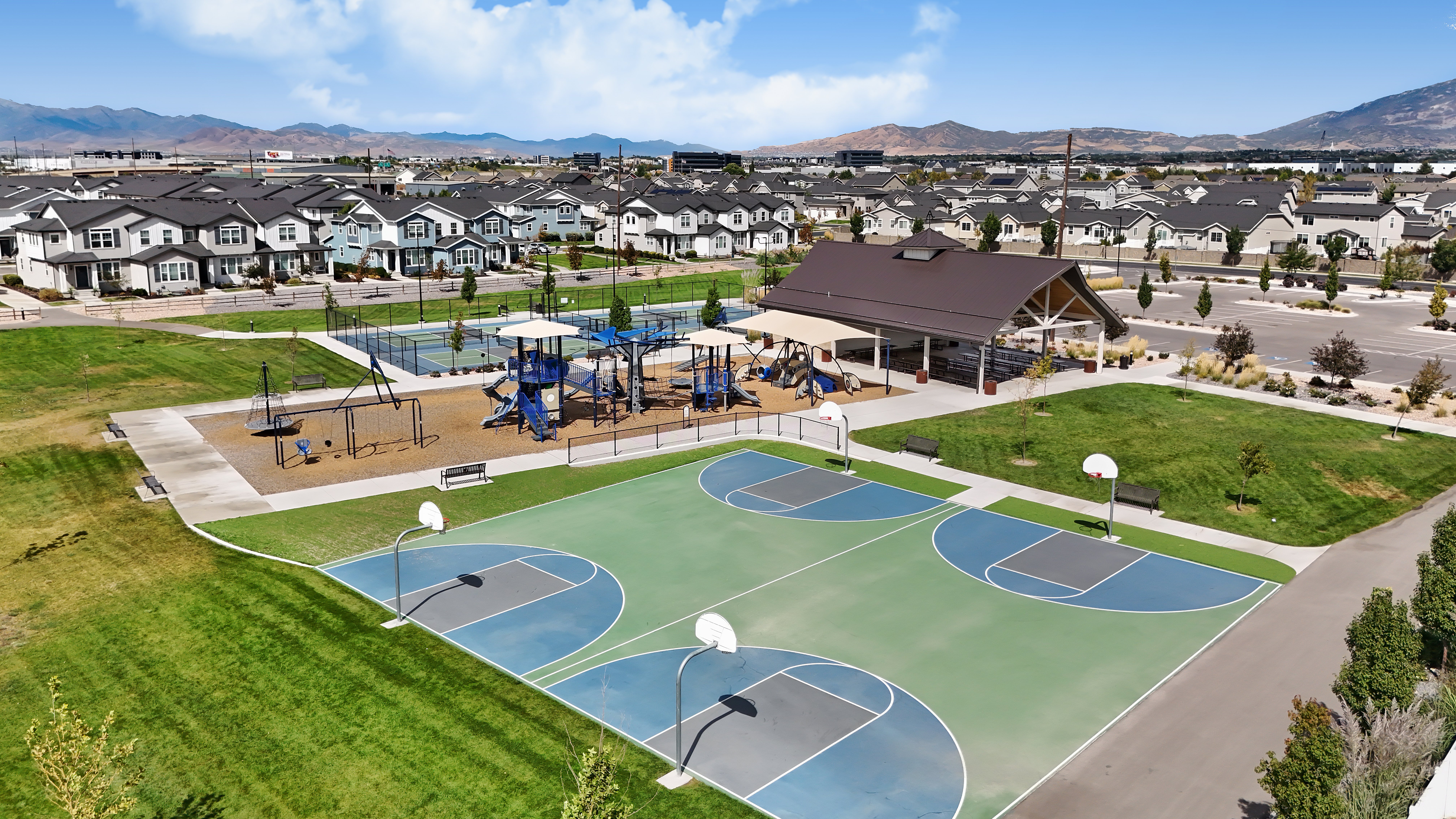 Community Park with Playgrounds and Basketball Courts Aerial view of a community park featuring playground equipment, basketball courts, and residential buildings in the background.