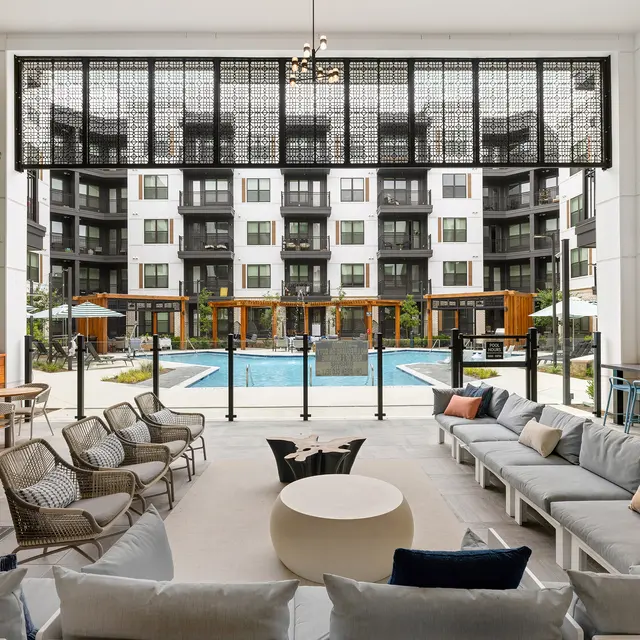 A stylish indoor lounge area with comfortable seating overlooking a pool and outdoor space.