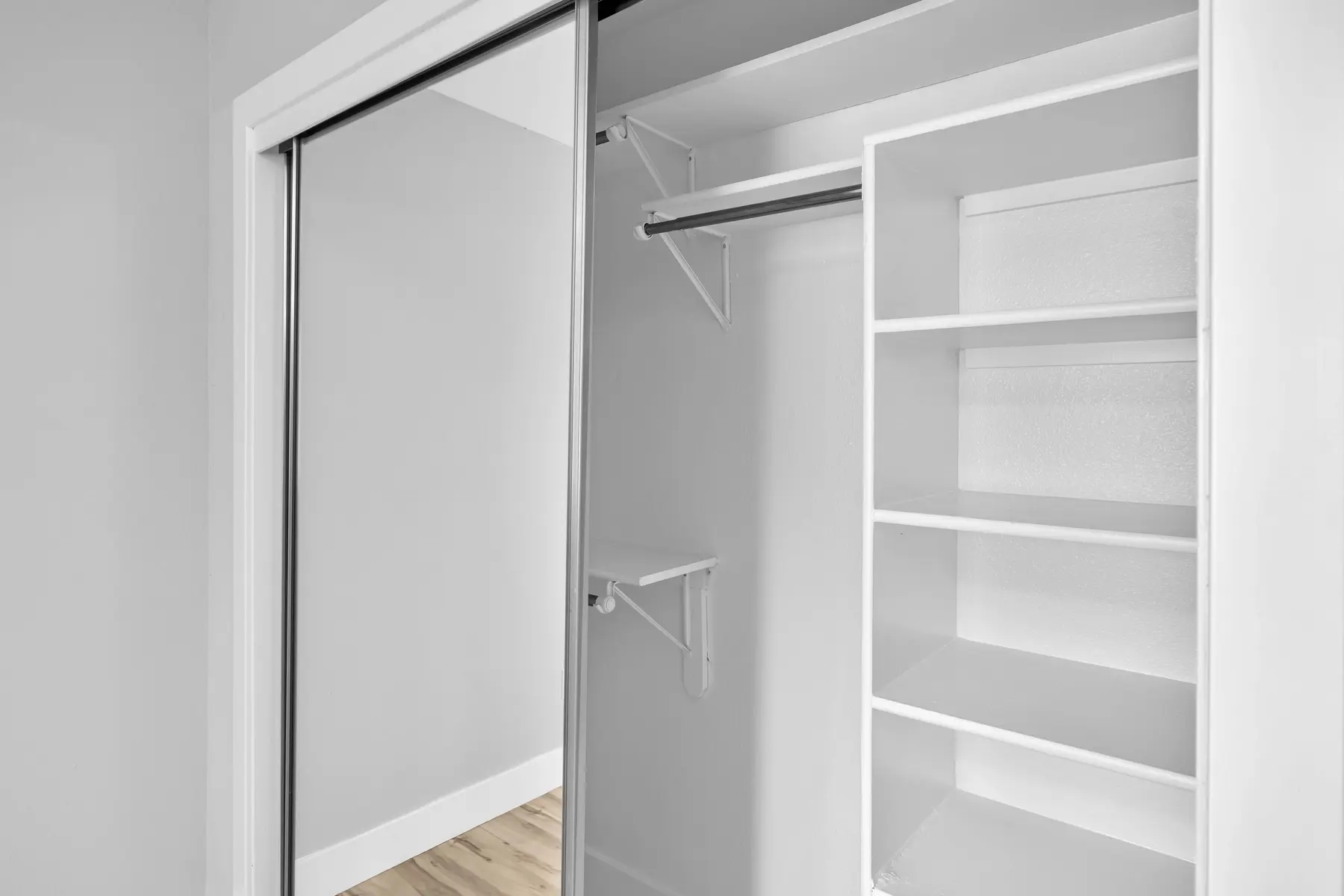 Interior view of a modern closet with sliding doors, featuring organized shelves and a clothing rod.