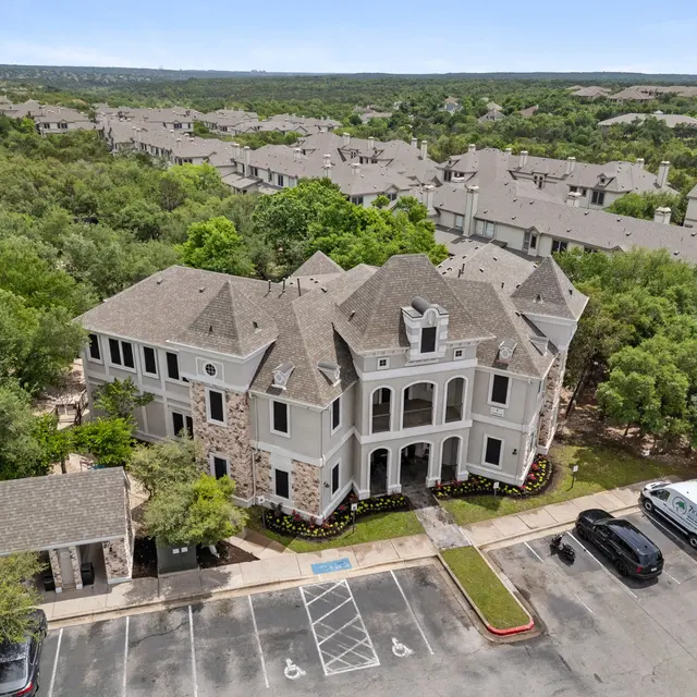 Aerial view of a large apartment complex surrounded by greenery and other buildings.