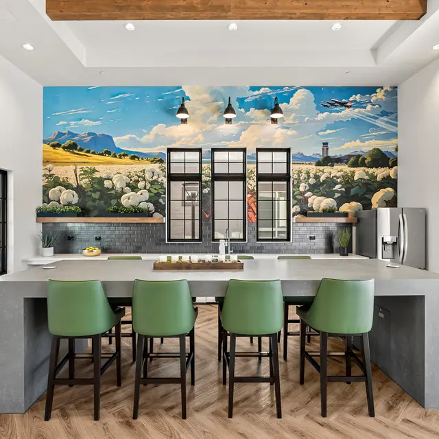 Modern Kitchen Design with Artistic Mural A modern kitchen with a large island, green bar stools, and a colorful mural depicting a landscape on the wall.