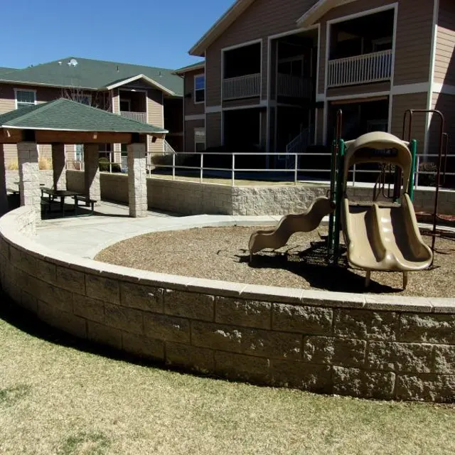 A playground area featuring a slide and a nearby gazebo within an apartment complex.