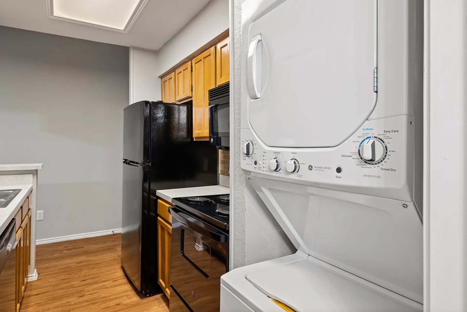Modern Kitchen with Washer and Dryer View of a kitchen featuring a black refrigerator, wooden cabinets, and a stacked washer and dryer unit.