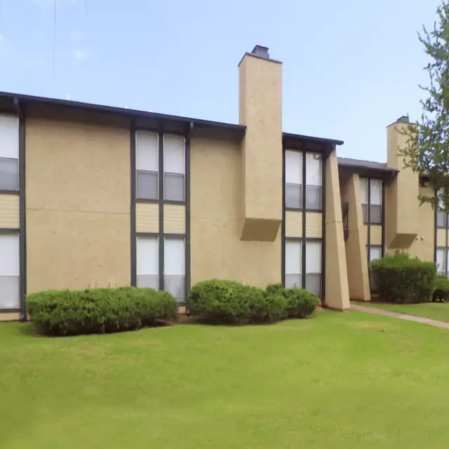 Modern Apartment Building Exterior view of a two-story apartment building with a well-maintained lawn and shrubs in front.