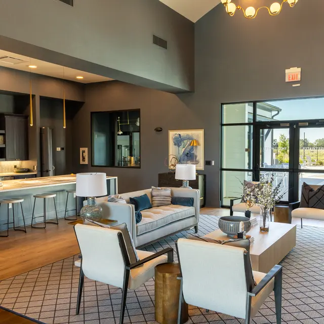 A modern living room with a stylish arrangement, featuring a gray wall, a large window, and a comfortable seating area with contemporary furniture.