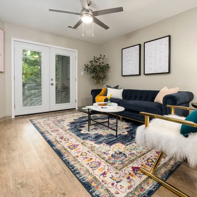 Cozy living room with a navy sofa, decorative pillows, a coffee table, and art on the walls, featuring natural light and wood floors.