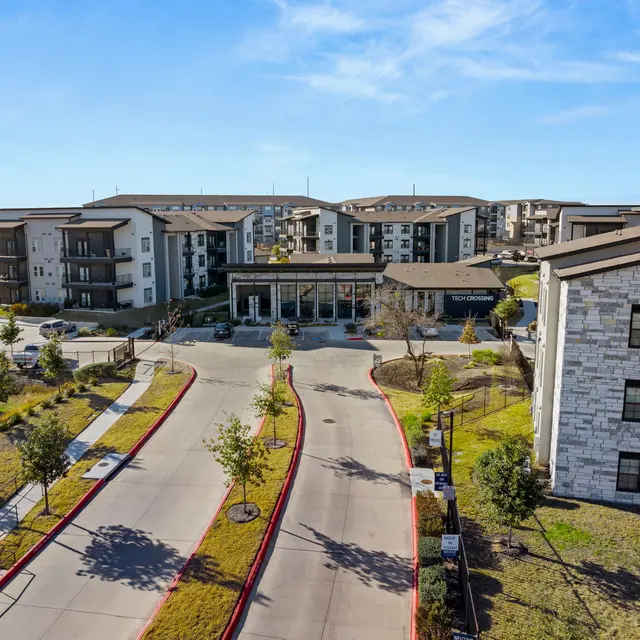 Aerial view of a modern apartment complex with landscaped grounds and parking areas.