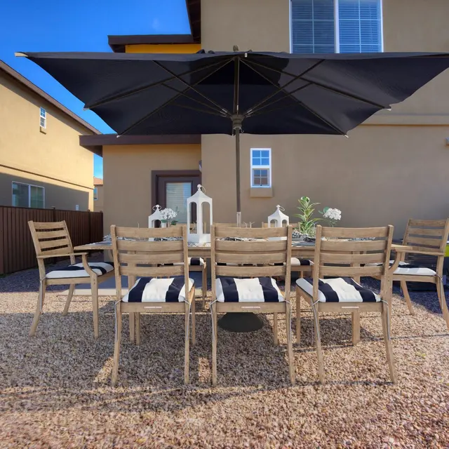 Outdoor Dining Area An outdoor dining area with a large table and chairs under a black umbrella.