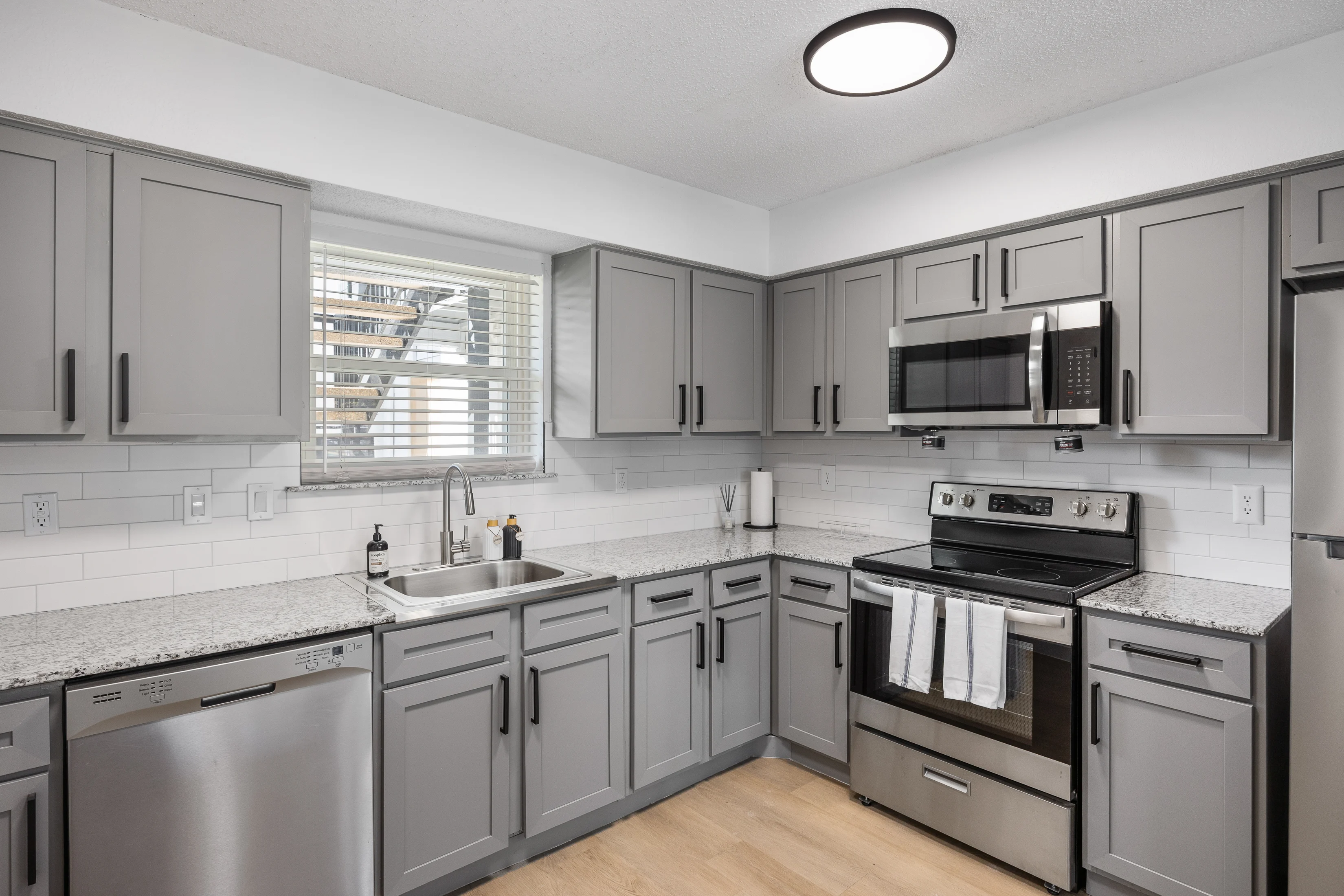 Modern Kitchen Interior A modern kitchen with gray cabinetry, stainless steel appliances, and a light wood floor.